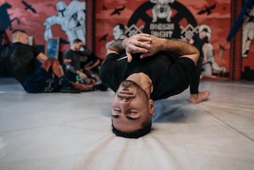 Man lying on the gym floor during MMA training, surrounded by athletes