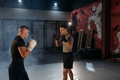 Free Two men engaged in an intense MMA training session indoors with boxing gear. Stock Photo
