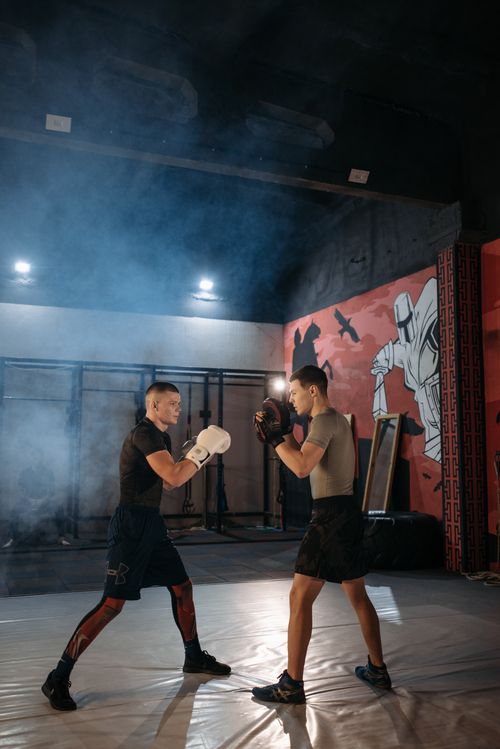 Free Two men sparring in a smoky gym environment, engaging in combat training. Stock Photo
