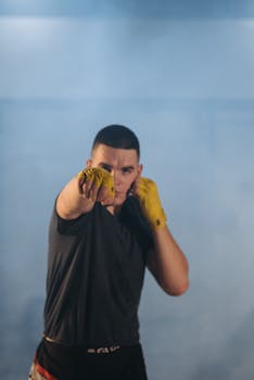 Boxer in action with yellow hand wraps delivering a punch during training in a gym.