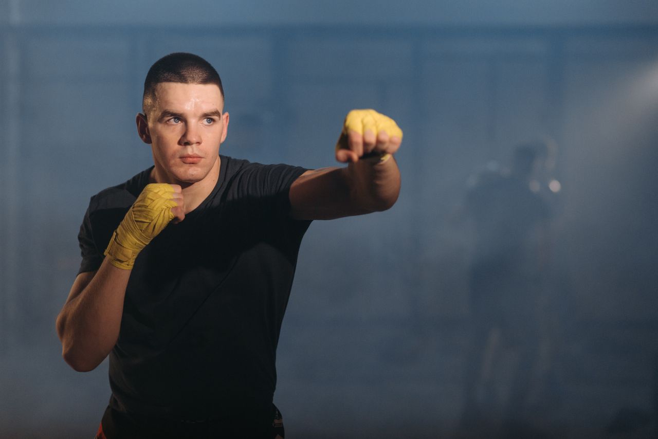 a male boxer performs shadow boxing in a dimly lit gym showing focus a