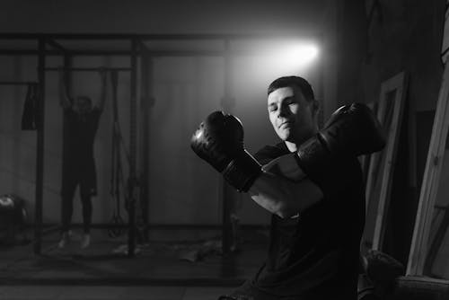 Grayscale Photo of a Man Wearing Boxing Gloves