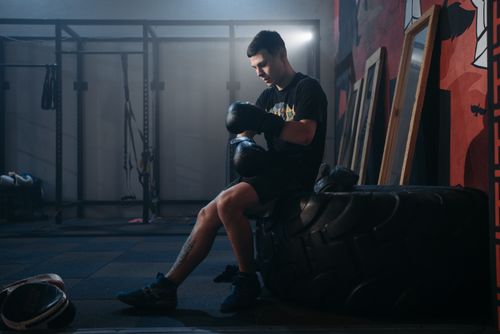 Free A boxer sits on a large tire in a gym, preparing for training. Stock Photo