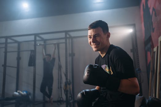 A young male boxer smiling during a training session inside a gym.