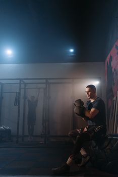 Man in black shirt and boxing gloves preparing for training in gym setting.