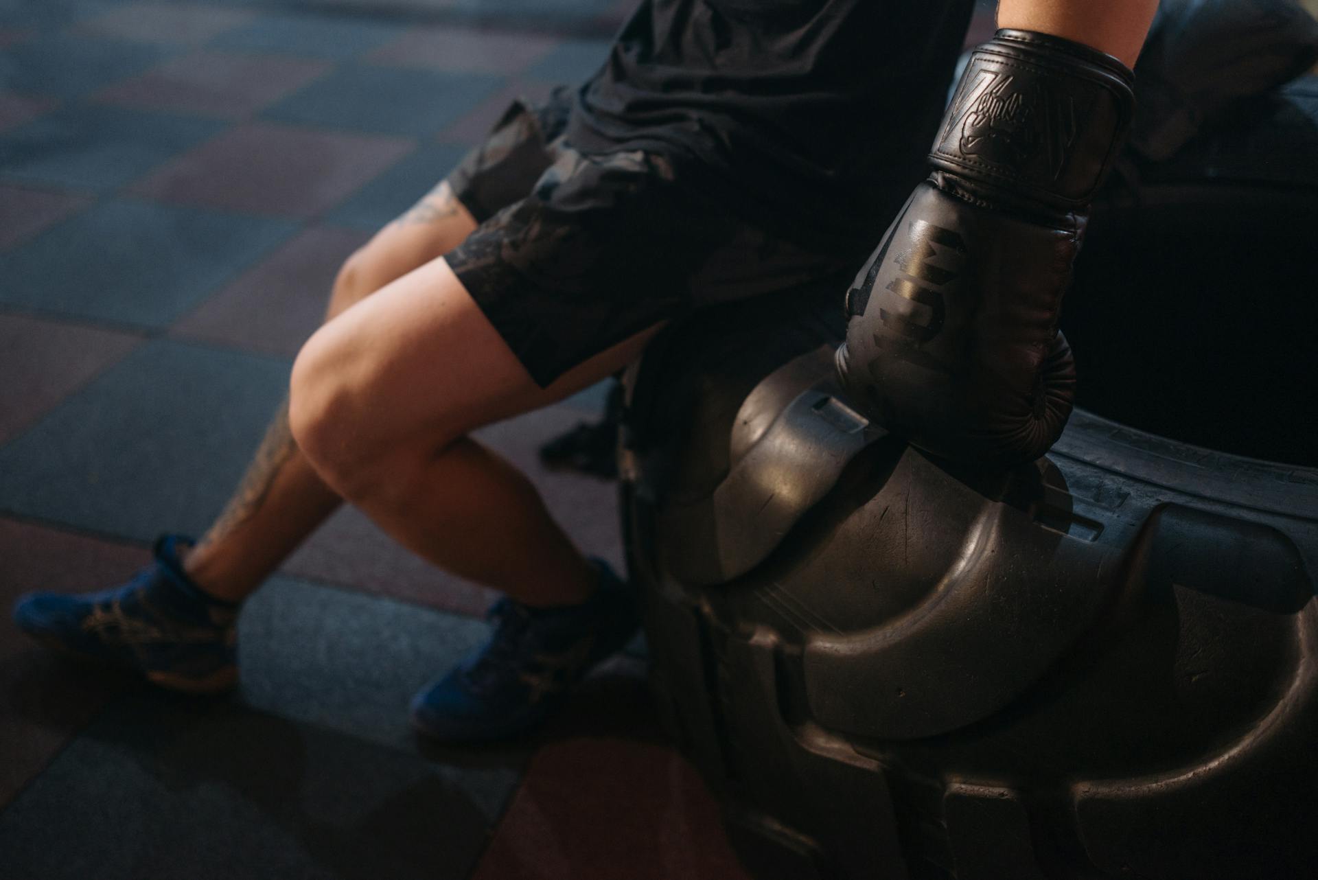 A Person Wearing Boxing Gloves Sitting on a Tire