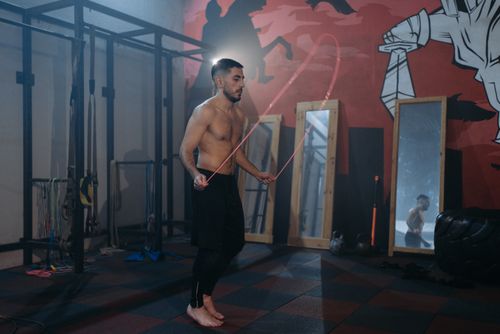 Free A muscular man performs jump rope exercise in a gym surrounded by mirrors. Stock Photo