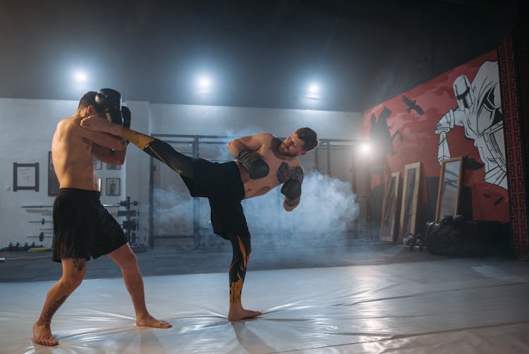 A Shirtless Man Blocking His Opponent's Kick