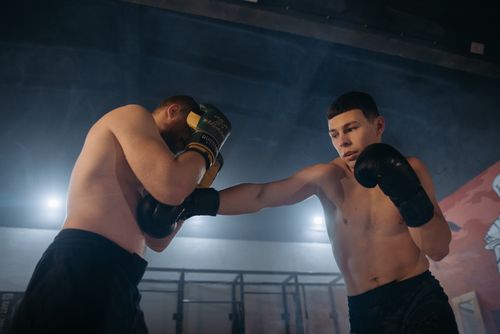 Free Two shirtless male boxers engaged in a gym sparring session wearing boxing gloves. Stock Photo