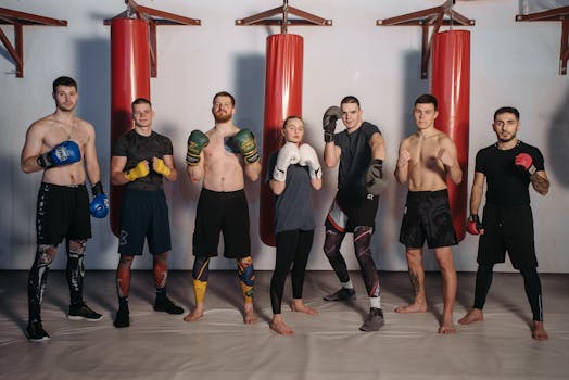 Boxers posing together in gym with punching bags, showcasing fitness and teamwork.