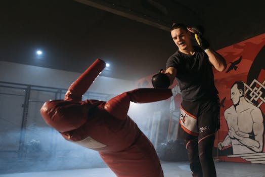 Martial artist training indoors, punching a red dummy with focus and intensity.