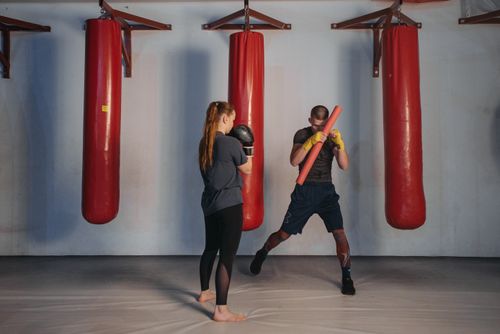 Free Coach and trainee practicing martial arts exercises using training bags indoors. Stock Photo