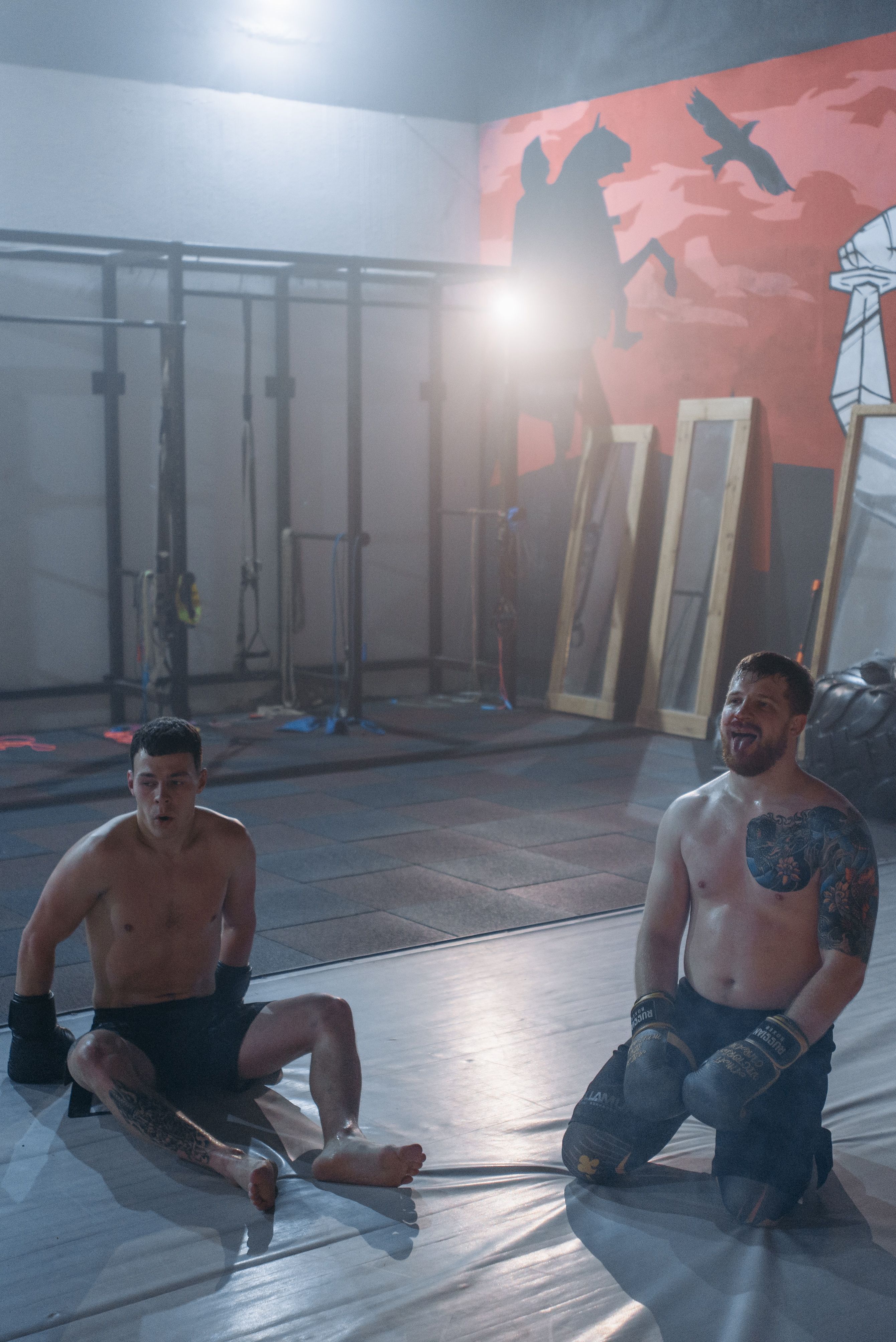 Two fighters resting on the mat after a round