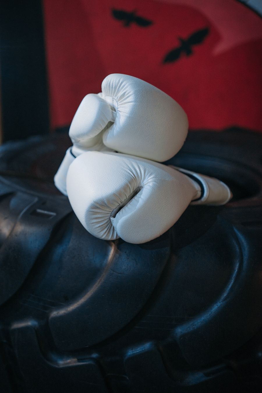 White boxing gloves resting on a tire