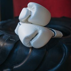 White boxing gloves resting on a punch bag