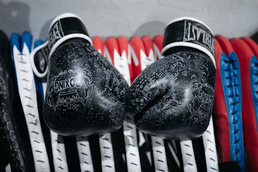 Black boxing gloves with embossed designs on a colorful background.