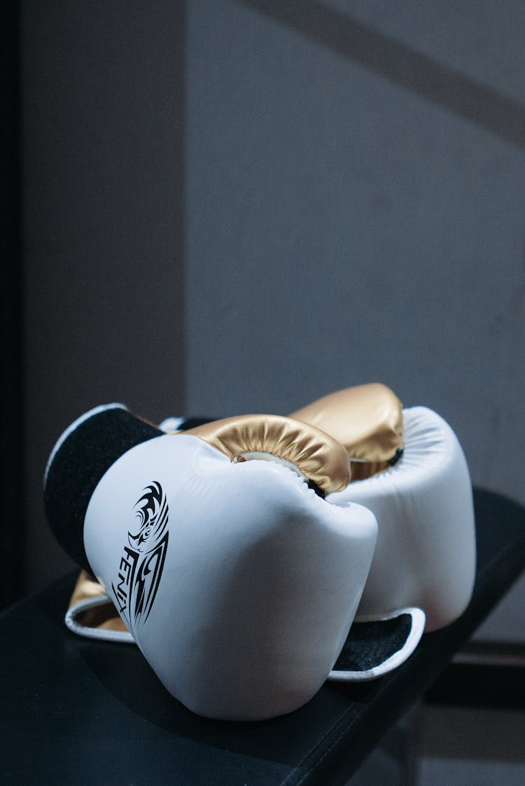 White And Gold Boxing Gloves On Black Surface