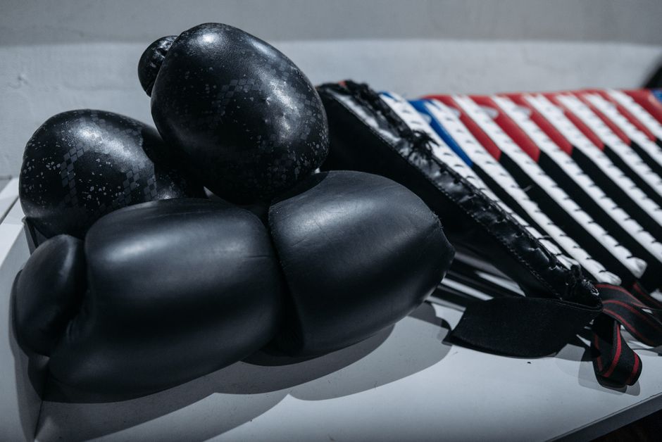 A pair of worn boxing gloves and shin guards representing typical kickboxing gear prices.