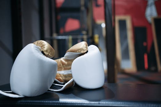 Close-up of elegant gold and white boxing gloves on a dark surface, perfect for fitness or sports themes.