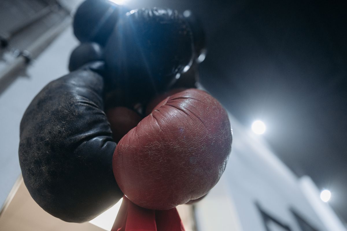 Close-up of red and black boxing gloves hanging in a gym