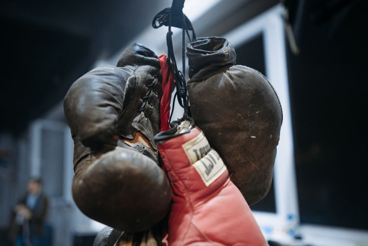 Vintage and modern boxing gloves hanging side by side in a gym, illustrative photo