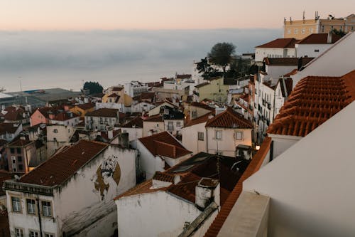 Small town with aged houses on hill against sea with clouds in sunset