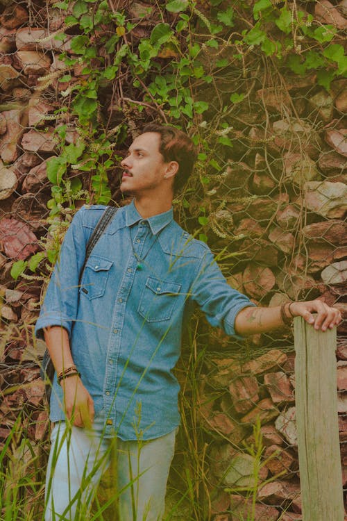 Pensive man standing near stone wall