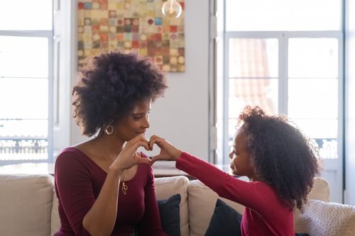 Free A mother and daughter creating a heart shape with their hands, expressing love and connection. Stock Photo
