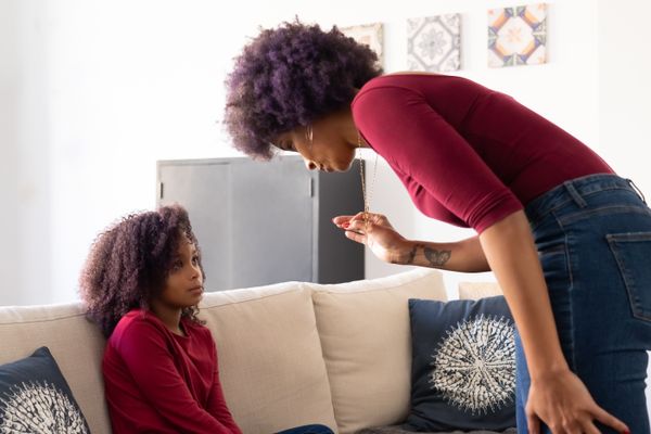 A mother and daughter sit on a couch having a serious conversation at home