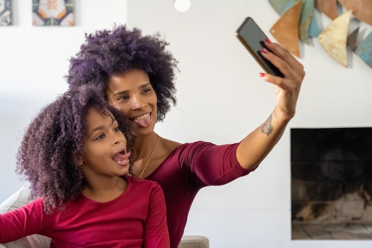 Mother And Daughter Taking A Selfie And Sticking Their Tongues Out 