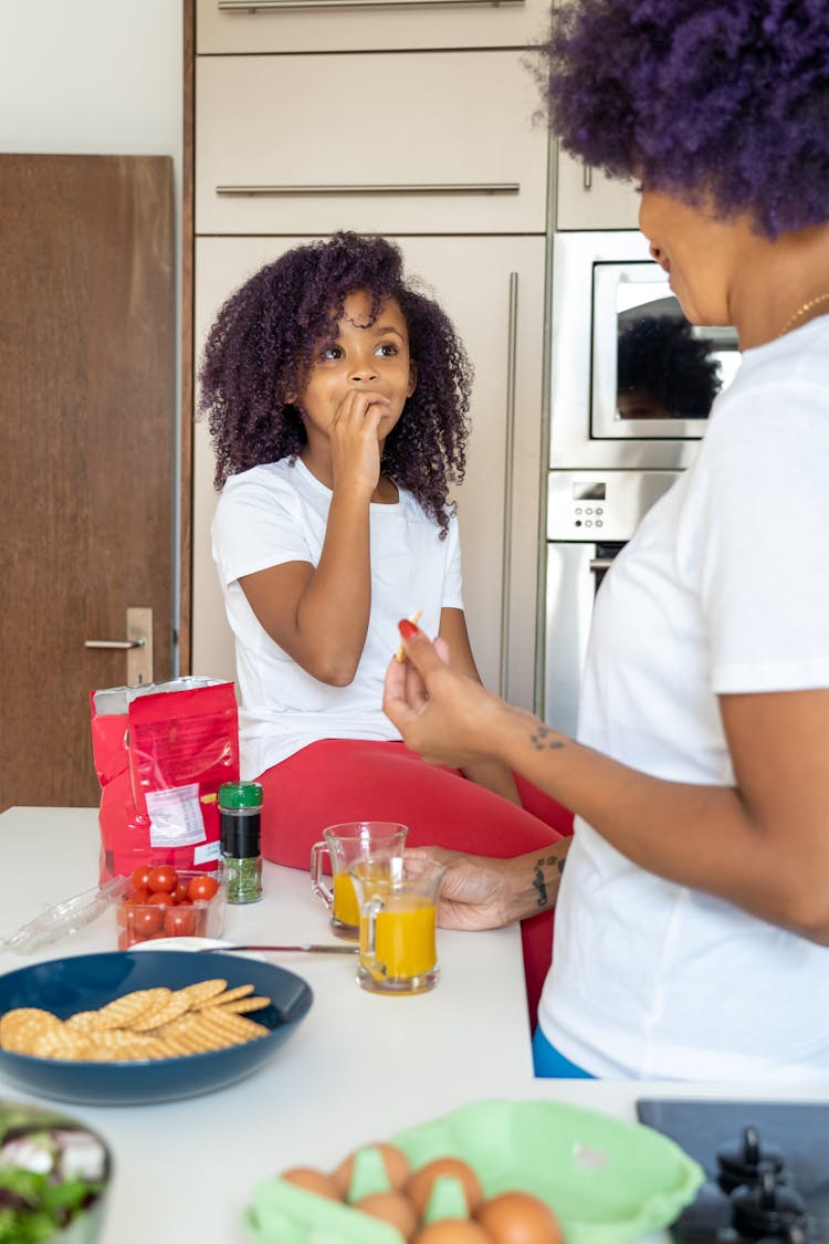 A Mother And Daughter Eating In The Kitchen