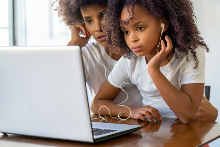 A Woman And Girl Looking In The Laptop