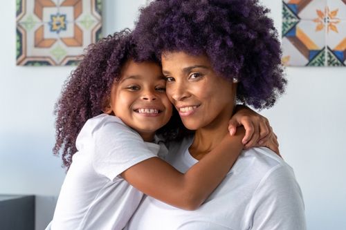 Free A joyful embrace between a smiling mother and daughter indoors, capturing love and togetherness. Stock Photo
