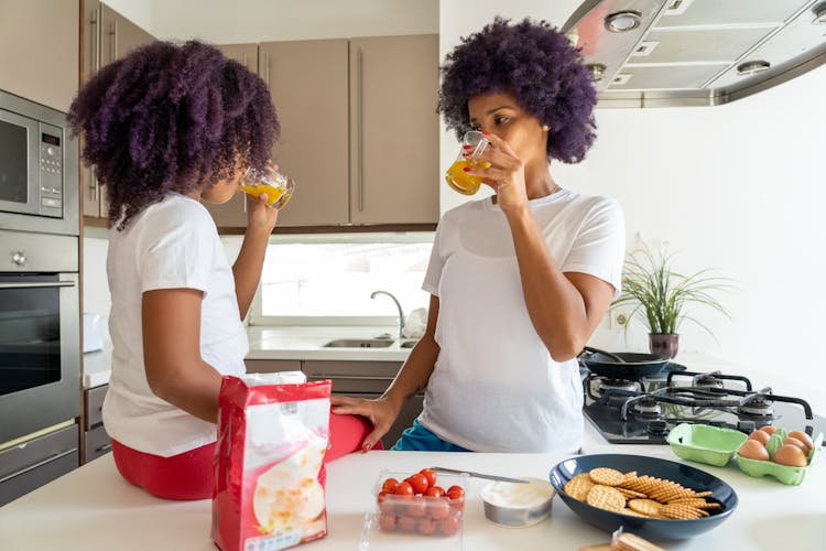 A Woman Drinking Juice With Her Daughter