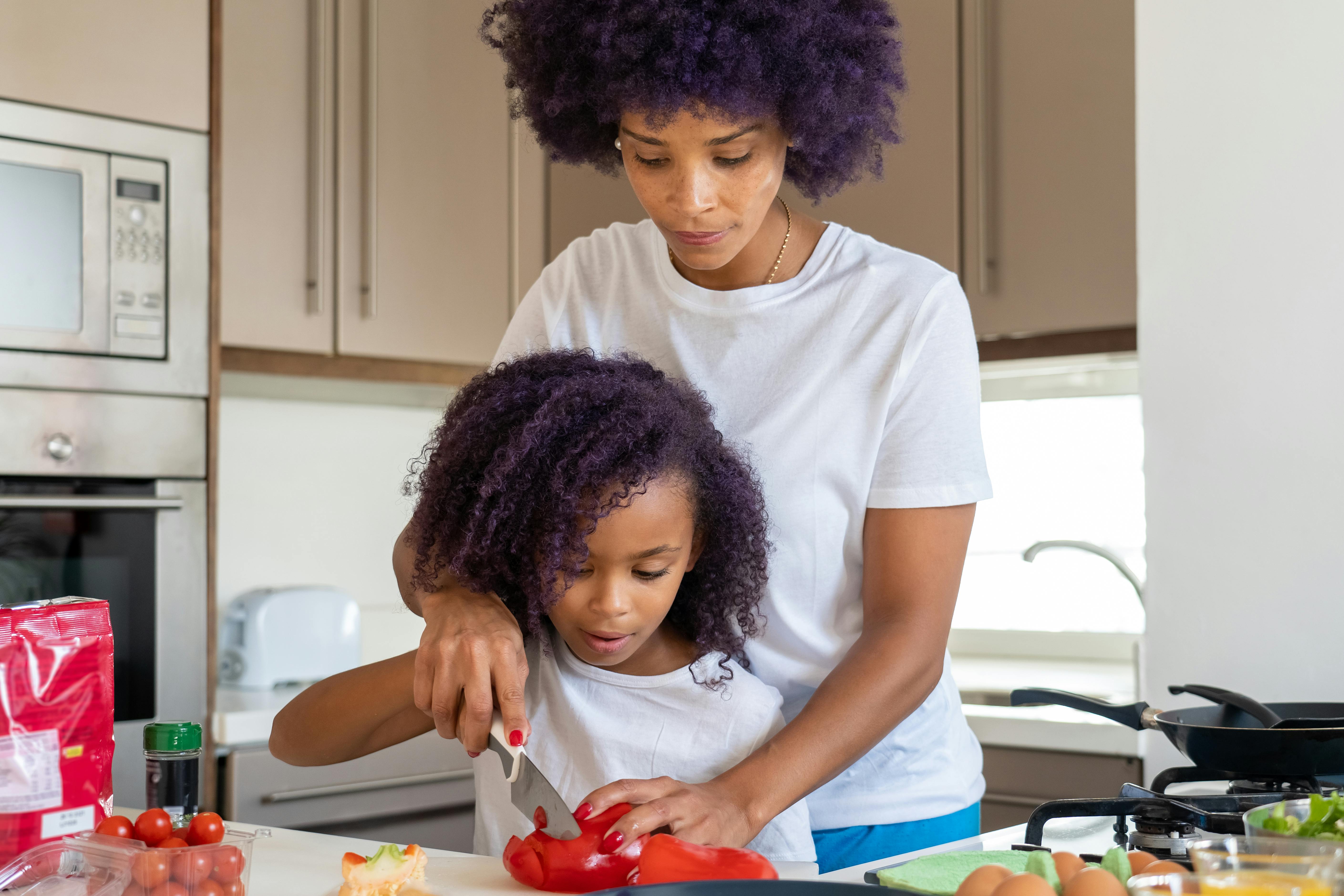 a mother and daughter slicing a bell pepper