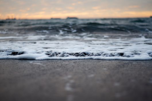 Calm ocean waves meeting sandy beach during a picturesque sunset. Perfect for relaxation themes.
