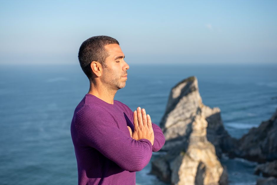 Como a Meditação Pode Aumentar sua Autoestima Diariamente 2 Side view of a man meditating by the ocean cliffs in Portugal, promoting relaxation and mindfulness.