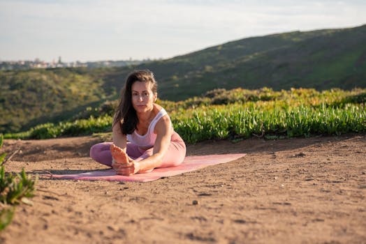 Woman in activewear stretching on a yoga mat in a scenic outdoor setting in Portugal.