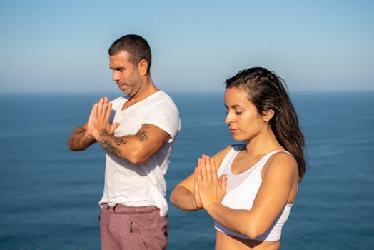 A couple enjoying yoga and meditation with a serene ocean backdrop in Portugal.