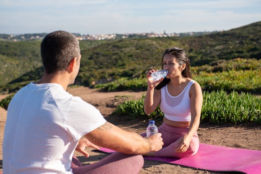 A man and woman enjoy an outdoor yoga session with water bottles in the scenic hills of Portugal.
