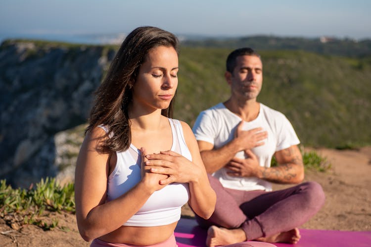 Woman And Man Doing Yoga Pose On Mountain Area