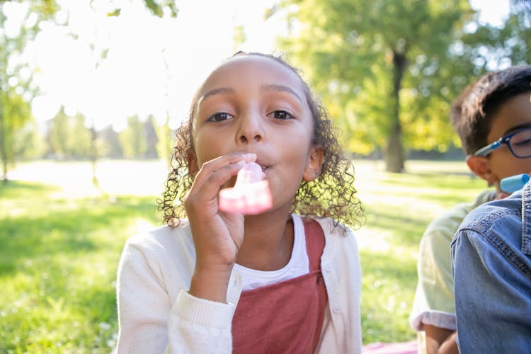 A Girl Blowing A Whistle Toy