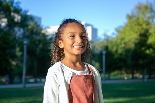 Free A joyful young girl smiling on a sunny day in a park, showcasing happiness and youthfulness. Stock Photo