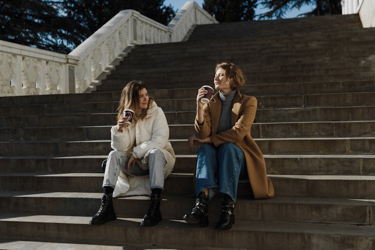 Women Holding Drinks While Sitting On Stairs