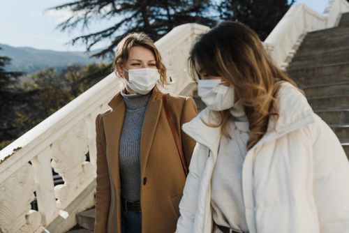 Free Two women wearing face masks walking down stairs outdoors during the day. Stock Photo