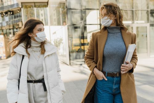 Free Two women wearing masks walking outdoors on a sunny day, embracing the new normal. Stock Photo