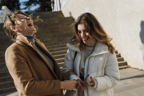 Two friends laughing together on a sunny street &mdash; photo by Arina Krasnikova on Pexels