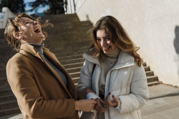 Two friends laughing together outside on a sunny day, photo by Arina Krasnikova on Pexels