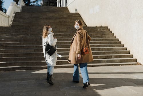 Femme En Chemise à Manches Longues Blanche Et Jean Bleu Denim Debout à Côté De Femme En Manteau Marron