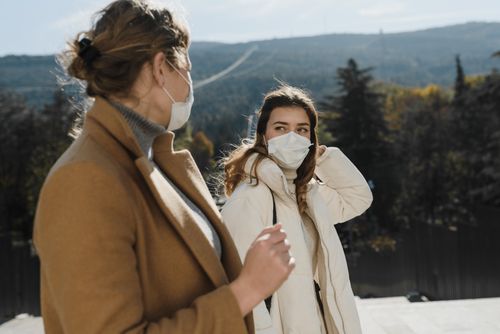 Free Two women with face masks conversing in an outdoor setting during daytime. Stock Photo
